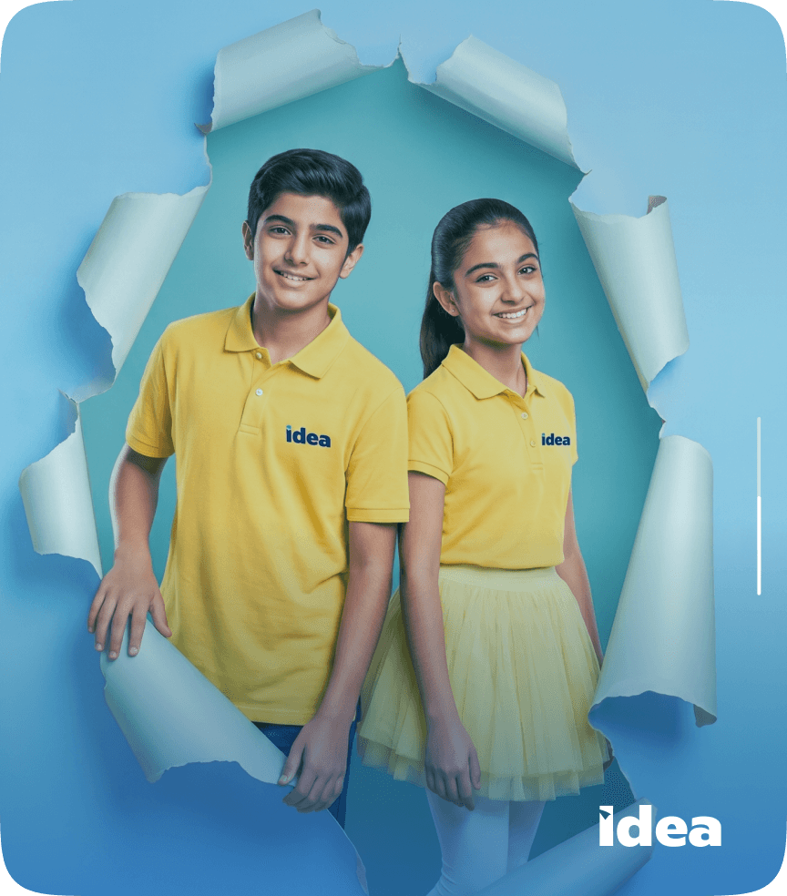 Two IDEA students in uniform stepping through a torn paper backdrop